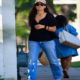 off her style in a lowcut black blouse and straight legged jeans. She paired the look with black mesh sandals